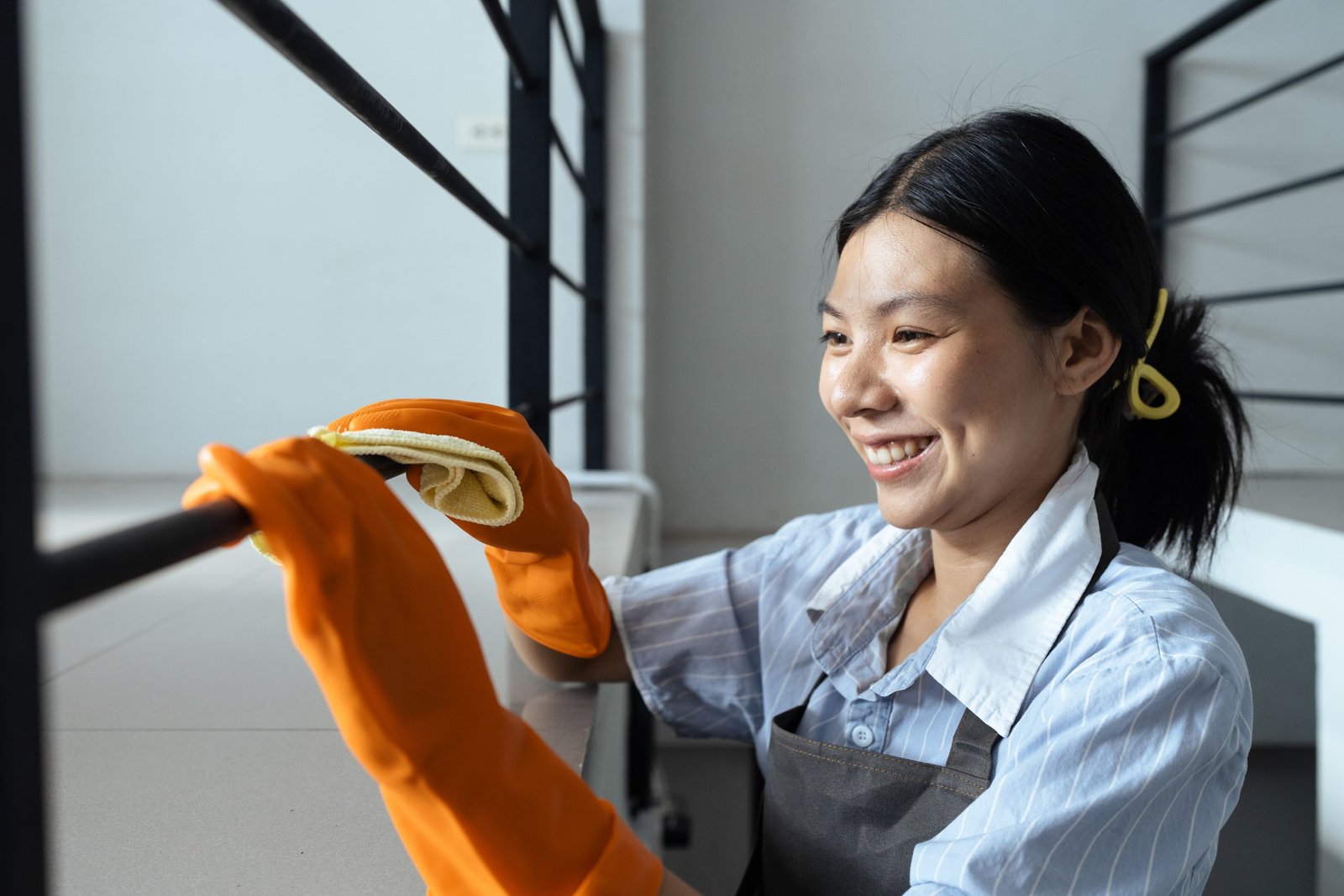 Hands in blue rubber gloves holding microfiber cleaning cloth make cleaning and disinfection for good hygiene of a stair railing Hands in blue rubber gloves holding microfiber cleaning cloth make cleaning and disinfection for good hygiene of a stair railing